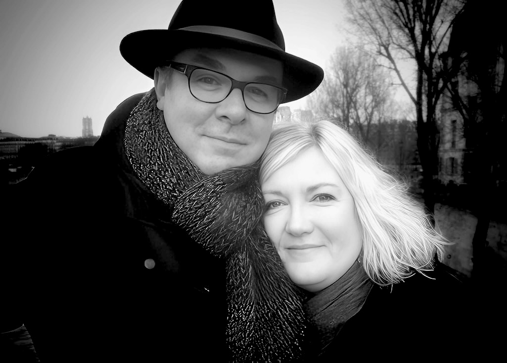 Geoffrey Clow and Georgie Bailey smiling together in Paris in winter, black-and-white photograph, looking in love.
